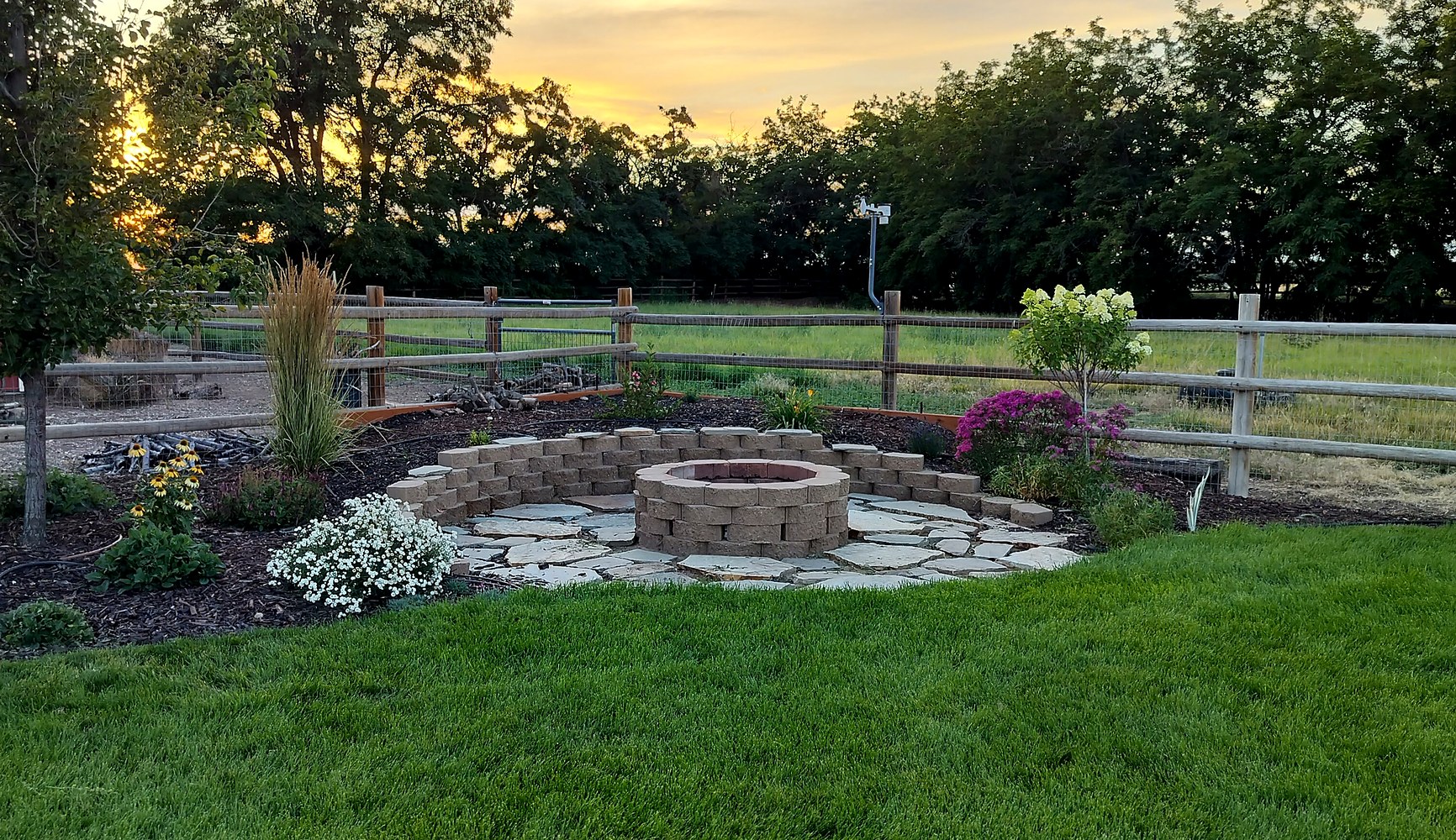 Landscape project with fire pit, stonework, beds, and lawn maintained by Green Grin